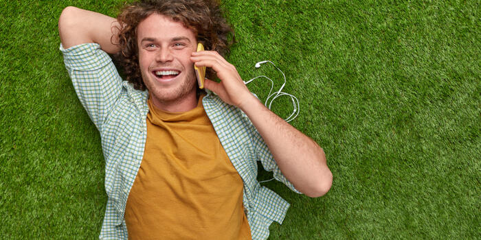 pocitovka muž se válí na trávě a telefonuje